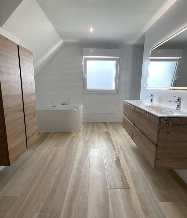 Salle de bains sol en carrelage effet bois, baignoire ilot, mur en carrelage effet vague blanc